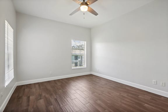 A room with a ceiling fan and wooden flooring.